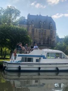um grupo de pessoas em um barco na água com um castelo em Le bateau du Foudre em Châtillon-en-Bazois