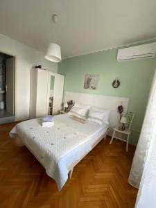 a bedroom with a white bed and a wooden floor at Apartmani Zorica in Rab