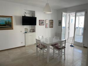 a white dining room with a white table and chairs at Villa Portinente in Lipari