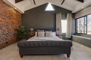 een slaapkamer met een groot bed in een bakstenen muur bij HAVANA VILLA - Pretoria East Luxury Villa in Pretoria