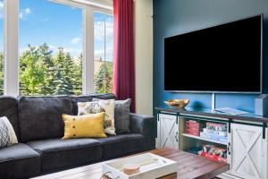 a living room with a couch and a flat screen tv at Modern home with a pool sauna pooltable & mountain view in Collingwood +41 photos