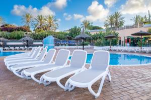 Una fila de sillas blancas junto a una piscina. en HL Club Playa Blanca, en Playa Blanca