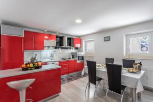 a kitchen with red cabinets and a table with chairs at Holiday house Mala in Sinj