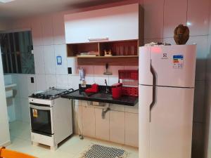 a kitchen with a white refrigerator and a stove at Apartamento aconchegante em Luis Correia in Luis Correia