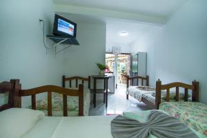 a bedroom with three beds and a tv on the wall at Hospedagem La Bilbaina in Porto Seguro