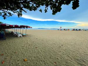 a beach with tables and umbrellas on the sand at Beach Gallery House in Jomtien Beach