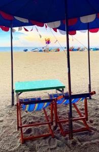 stół i krzesła na plaży pod parasolem w obiekcie Beach Gallery House w mieście Jomtien Beach