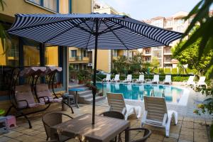 a table with an umbrella in front of a pool at Aquaria Holiday Apartments in Sunny Beach