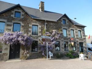 un edificio de ladrillo con una corona de flores púrpuras. en Le Relais, en Saint-Sauveur-la-Pommeraye