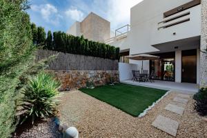 un patio trasero con una pared de piedra y un césped verde en Casita Rosa, en Alicante