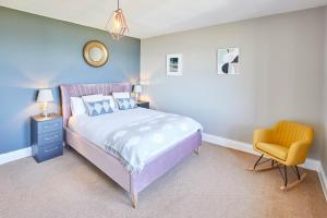 a bedroom with a bed and a yellow chair at Host & Stay - The Puffins Nest in Seahouses