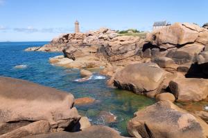 a rocky shore with a lighthouse in the background at Le cheval d’en fer in Bégard