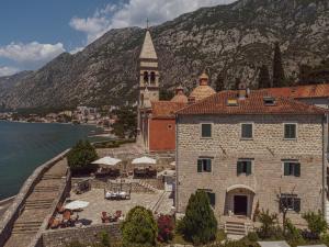 a building with a clock tower next to a body of water at Kamena Palata Apartments in Kotor