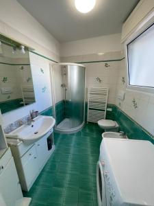 - une salle de bains verte et blanche pourvue d'une douche et d'un lavabo dans l'établissement Vista mare, à Misano Adriatico