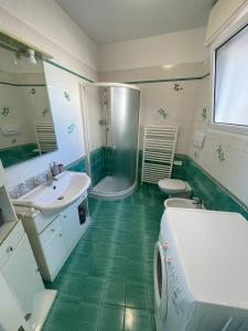 - une salle de bains verte et blanche pourvue d'une douche et d'un lavabo dans l'établissement Vista mare, à Misano Adriatico