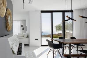 a living room with a table and chairs and a piano at White Hera in Agios Pavlos