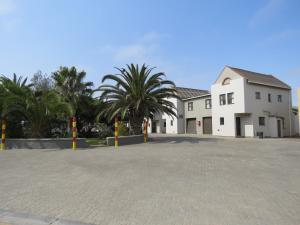 a large white building with palm trees in front of it at Lagoon Chalets in Walvis Bay