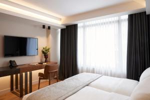 a hotel room with a bed and a desk and a television at Teight Hotel in Thessaloniki