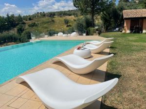 a group of white chairs sitting next to a swimming pool at Villa Greco in Rossano
