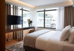 a bedroom with a bed and a desk with a television at Teight Hotel in Thessaloniki