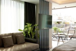 a living room with a couch and a television on a wall at Teight Hotel in Thessaloniki