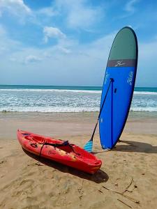 un kayak rojo y una tabla de surf azul en la playa en Halcyon Mawella, en Tangalle