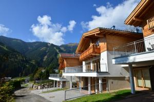 a building with a balcony and mountains in the background at Ski Chalet Jim by All in One Apartments in Zell am See