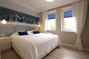 a bedroom with a white bed and two windows at Apartbaltic - Monte Cassino in Świnoujście