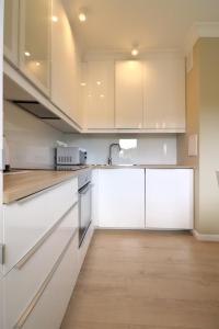 a kitchen with white cabinets and a wooden floor at Apartbaltic - Monte Cassino in Świnoujście