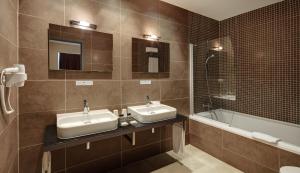 a bathroom with two sinks and a bath tub at Sercotel Plaza Feria in Zaragoza