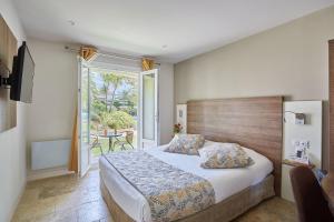 1 dormitorio con 1 cama y balcón con mesa en Logis Hôtel Le Rodin, en Arles