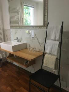 a bathroom with a sink and a mirror and a chair at La Pallanzotta in Verbania