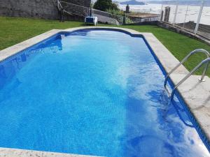 a large swimming pool with blue water in a yard at O Castro Sanxenxo in Sanxenxo