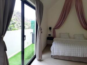 PombasHotel Château Georgette的一间带床和大窗户的卧室
