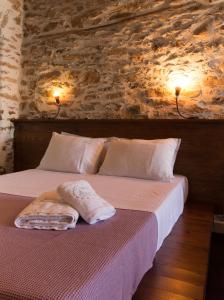 1 dormitorio con 1 cama con pared de piedra en To Petrino, en Agios Ioannis