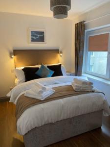 Location Location - Gorgeous 3 Bed Apartment in Killarney في كيلارني: غرفة نوم بسرير كبير عليها شراشف ووسائد بيضاء
