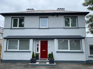 Location Location - Gorgeous 3 Bed Apartment in Killarney في كيلارني: منزل أبيض مع باب احمر