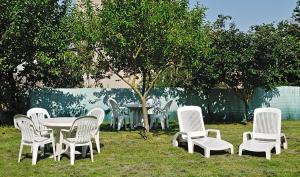 un grupo de sillas blancas, una mesa y un árbol en Logis Hôtel Restaurant Cazes Arazat, en Laissac