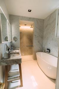 a bathroom with a tub and a sink and a shower at Hôtel Hemen in Saint-Palais-sur-Mer