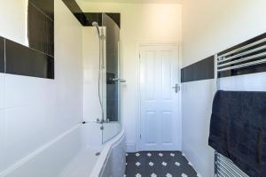 a white bathroom with a tub and a shower at Spacious 3BR House Near Southend Pier in Southend-on-Sea