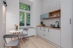 a kitchen with white cabinets and a table and chairs at Parkside Fresh Apartments - Old Town Guesthouse in Krakow