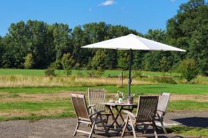 a table with a white umbrella and four chairs at B&B Joostink in Vorden in Vorden