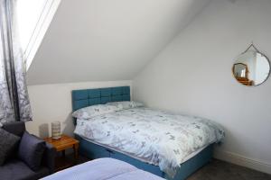 een slaapkamer met een bed met een blauw hoofdeinde en een spiegel bij Nineteen in Bridlington