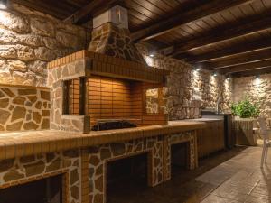 an outdoor kitchen with a stone fireplace in a house at Adonis Villa in nature in Ixia