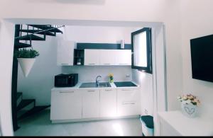 een keuken met witte kasten, een wastafel en een raam bij Dimora Asmara 11 15 in Brindisi