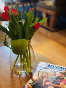 a vase with red tulips in it next to a magazine at Ferienwohnung Lofereck in Reit im Winkl