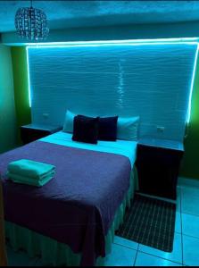 a bedroom with a bed with a blue light at Hotel Maya Copan Guamilito in San Pedro Sula