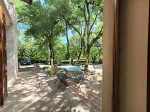- une table et des chaises sur une terrasse couverte avec des arbres dans l'établissement L'Appartement des Esclargies, à Rocamadour