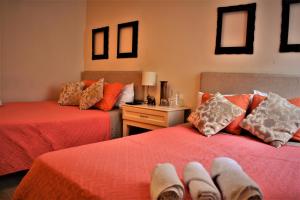 2 letti in una camera con lenzuola e cuscini rossi di Kangaroo Wasi Airport Bed & Breakfast a Lima