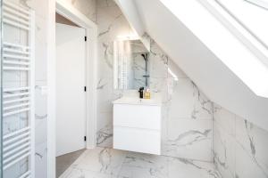 Baño blanco con paredes de mármol blanco y lavabo en Beautiful Central Cityflats, en Amberes